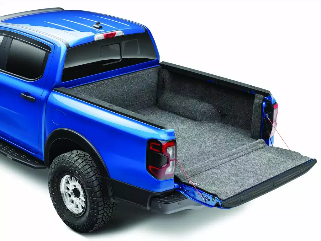 A blue pickup truck with an open cargo bed lined with gray carpet