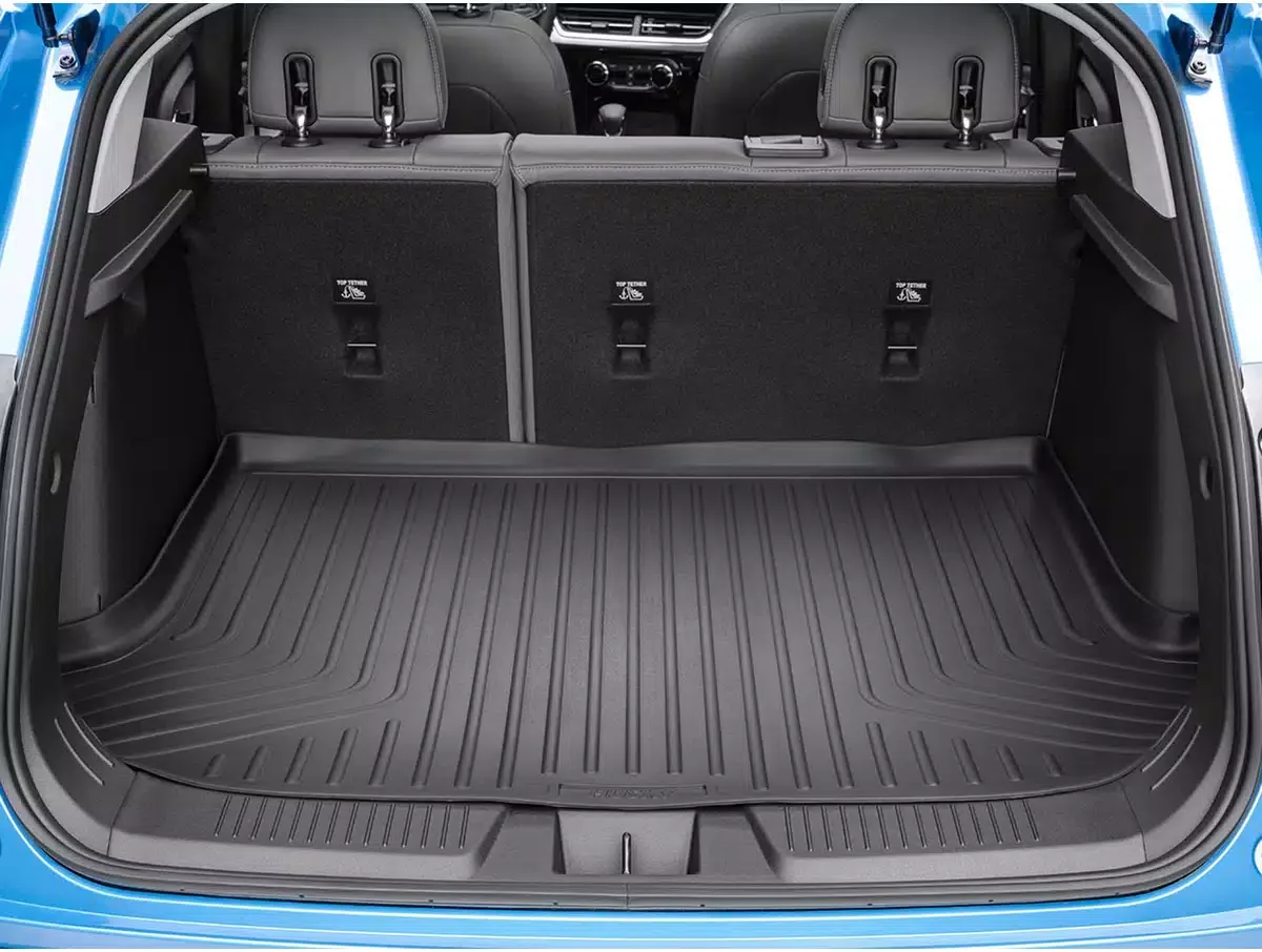 View of the empty cargo space of a blue hatchback car with a black rubber cargo mat and the back of the rear seats.