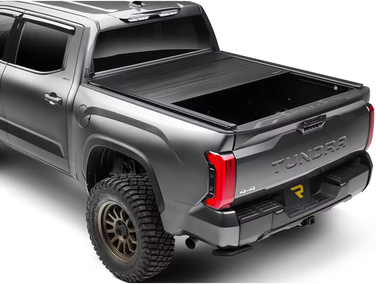 A gray Toyota Tundra pickup truck with a black tonneau cover over the truck bed, large off-road tires, and black accents.