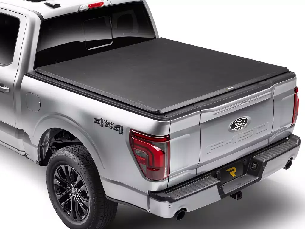 Silver Ford pickup truck with a hard tonneau cover over the bed and '4X4' emblem, shown from the rear, on a white background.