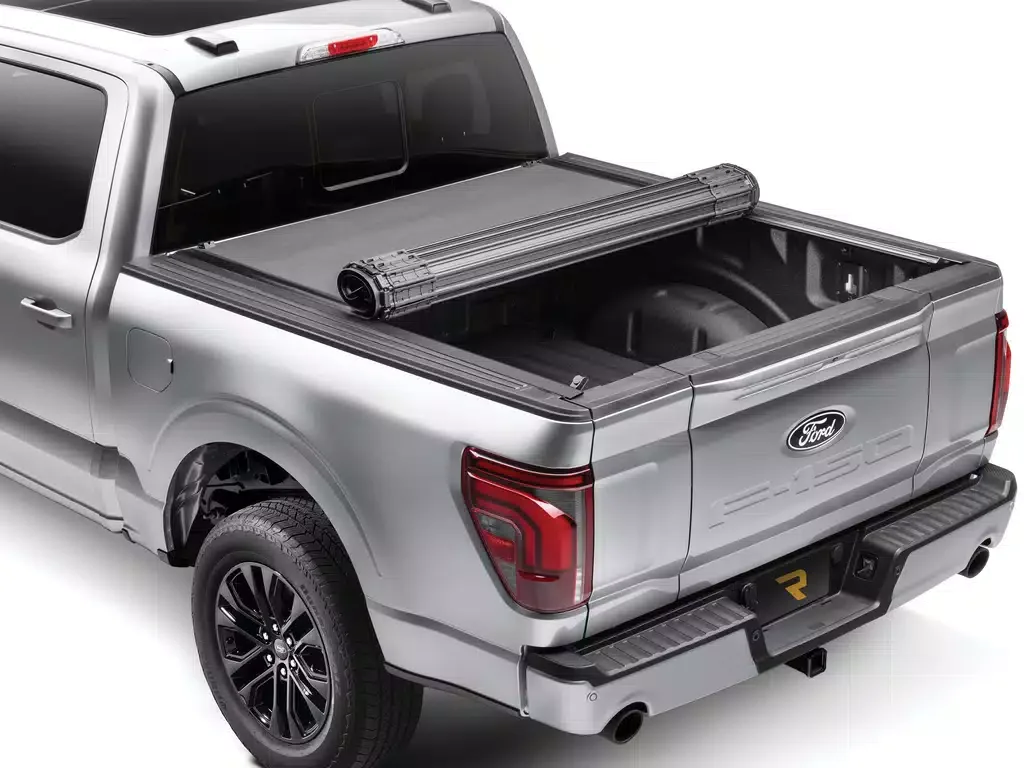 Silver Ford pickup truck with open cargo bed and a rolled-up tonneau cover, rear view, against a white background.