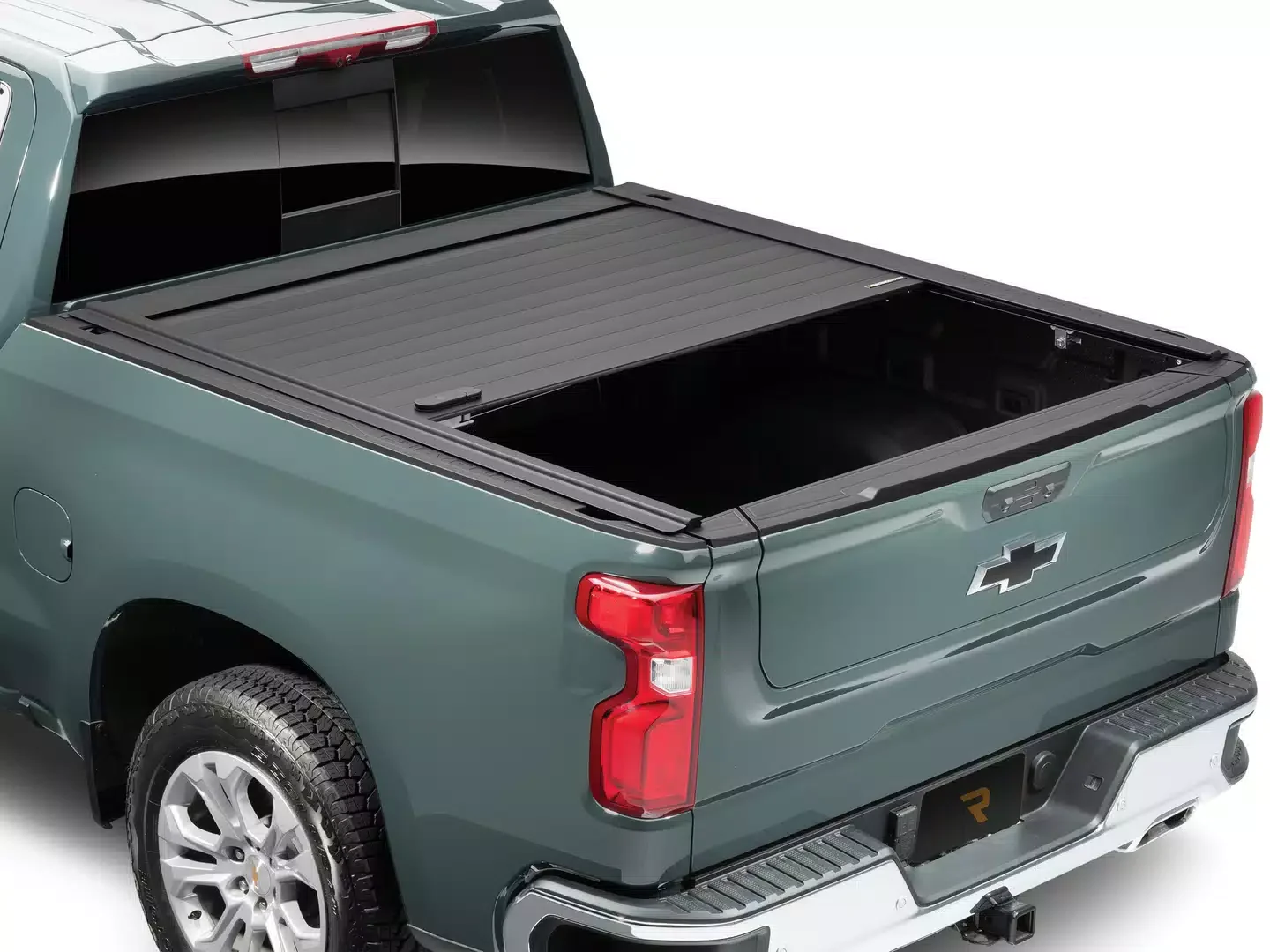 The back of a green Chevrolet pickup truck with an open truck bed featuring a black tonneau cover.