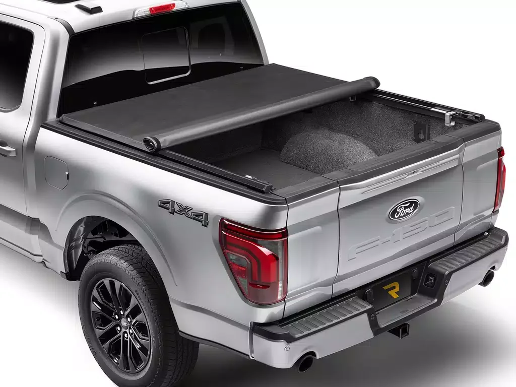 Silver Ford pickup truck with open bed, 4x4 logo, black and silver wheels, rear taillights, and a bed cover. The bed interior is visible.