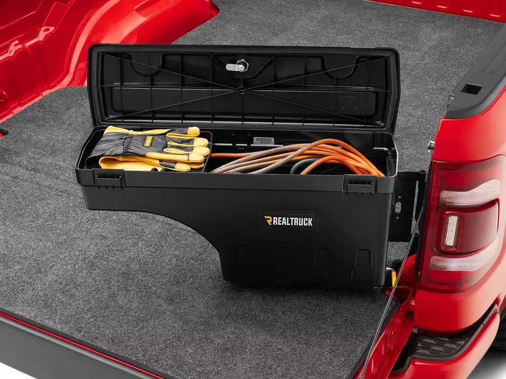 Open black toolbox in the truck bed with yellow gloves and various orange and brown extension cords inside.