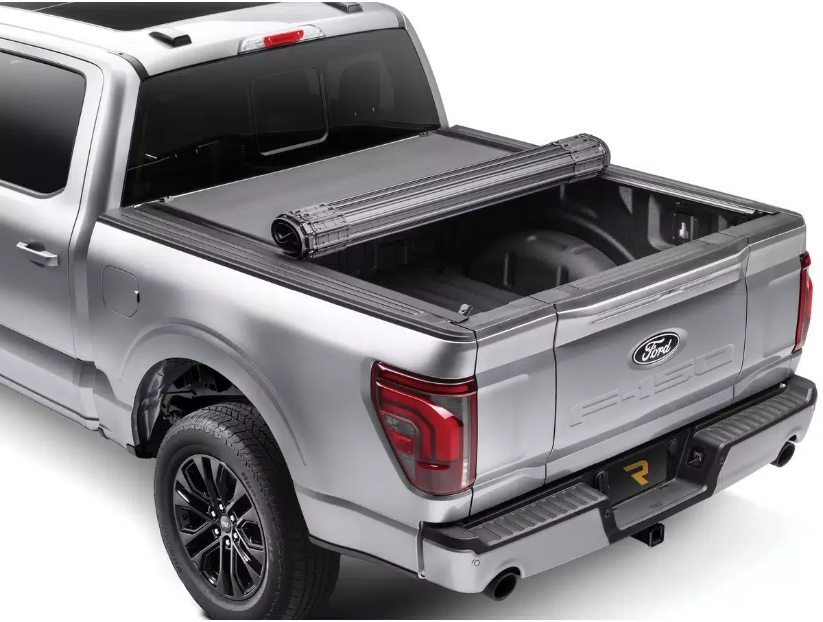 Silver Ford pickup truck with an open bed, featuring a rolled-up tonneau cover rolled at the front of the bed.