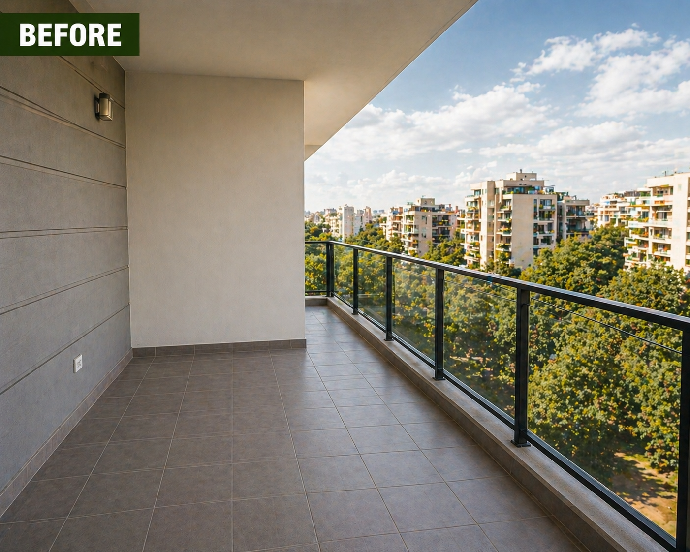 Empty balcony with tiled floor and glass railing, overlooking apartment buildings and trees under a partly cloudy sky.