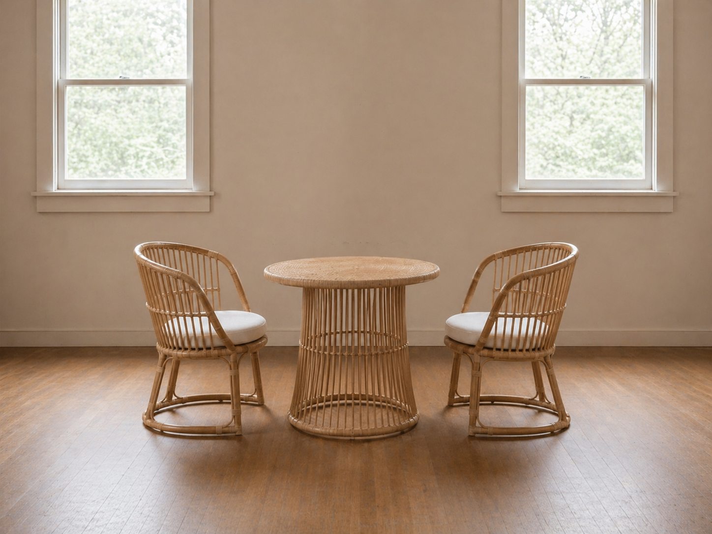 A minimalistic room with two windows, a rattan table, and two matching rattan chairs with white cushions.