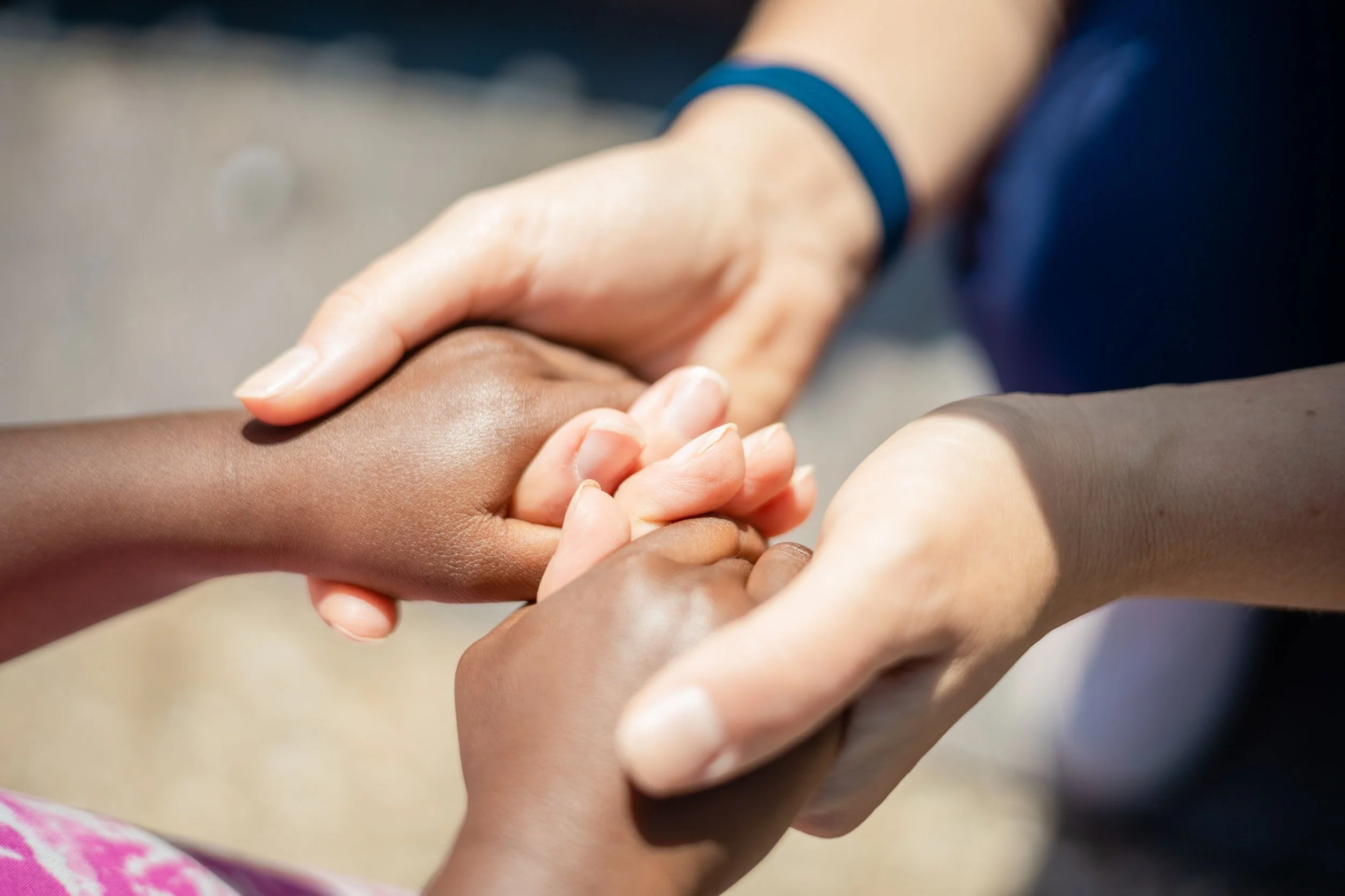 Close-up of multiple hands holding each other in a supportive gesture.