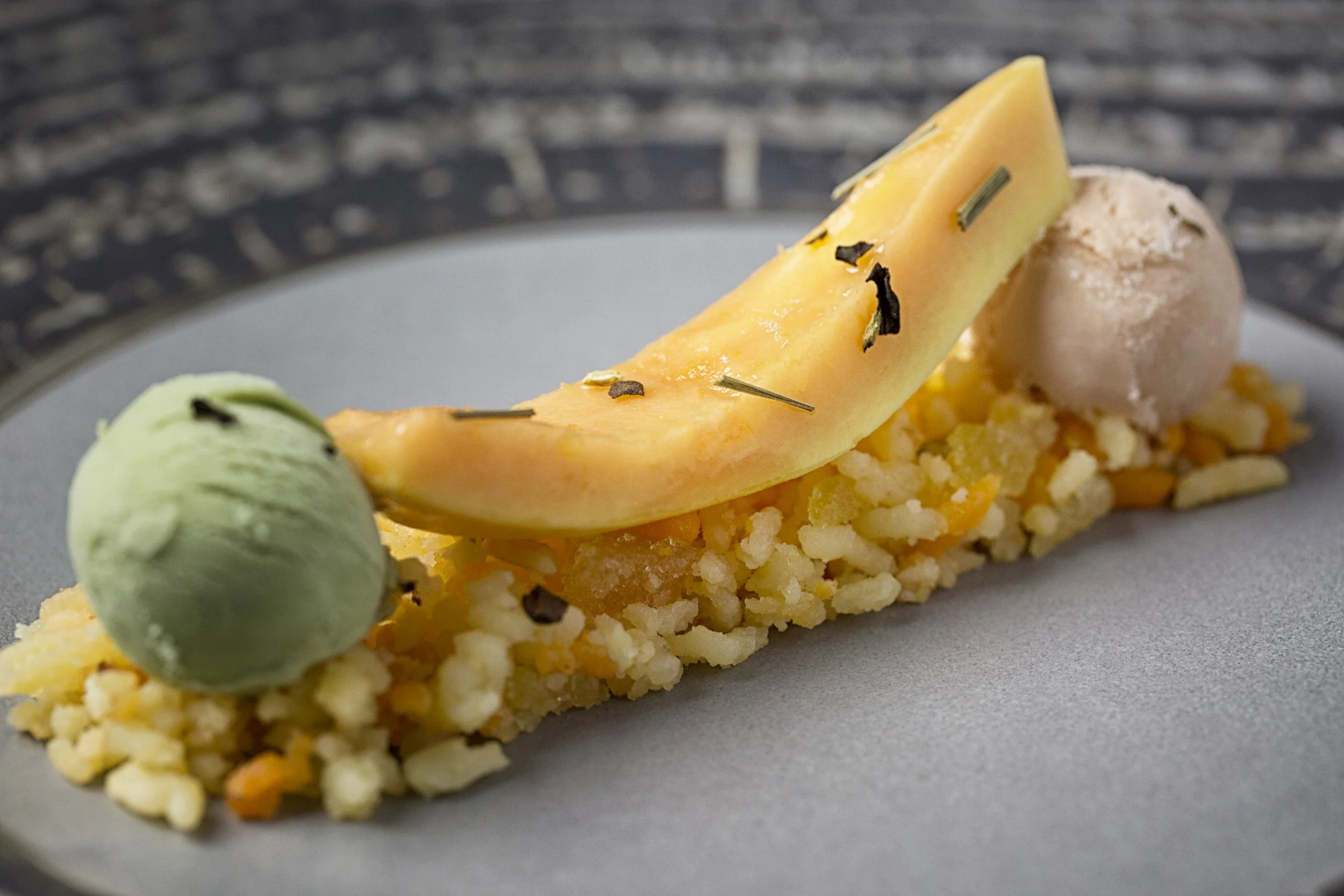 A slice of melon on top of a bed of rice, garnished with herbs and presented on a white plate.