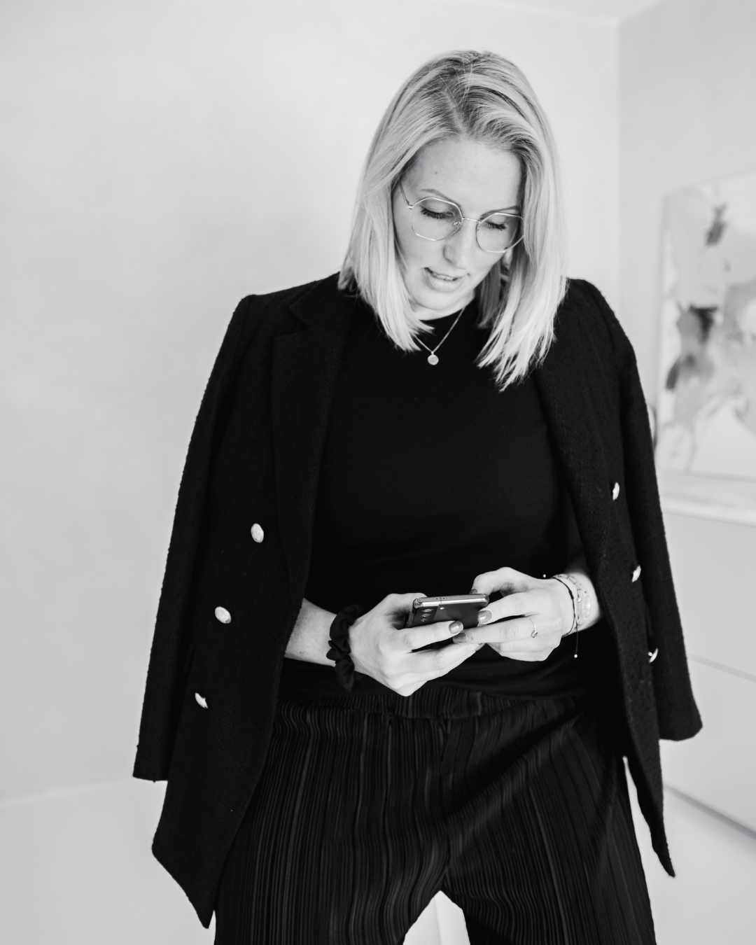 Johanna Sander, Copywriterin und Kurs-Creatorin, tippt konzentriert auf ihrem Smartphone – Schwarz-Weiß-Businessfoto
