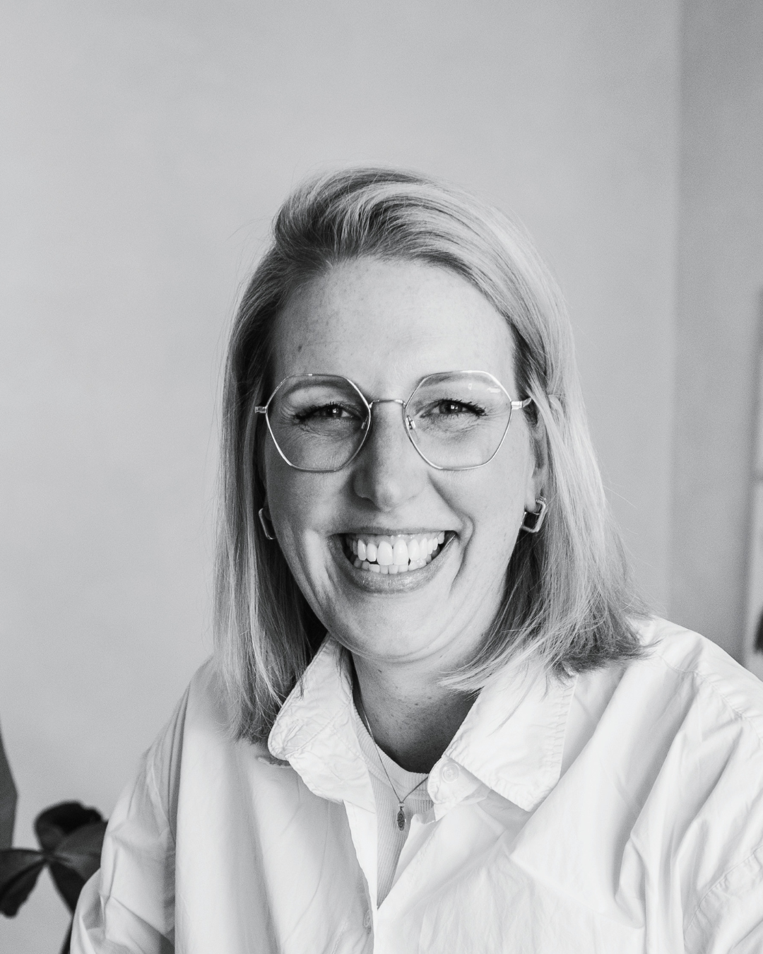 Johanna Sander, Business-Mentorin und Copywriterin hinter your gut, lacht herzlich in die Kamera – nahes Schwarz-Weiß-Porträt mit Brille und weißem Hemd