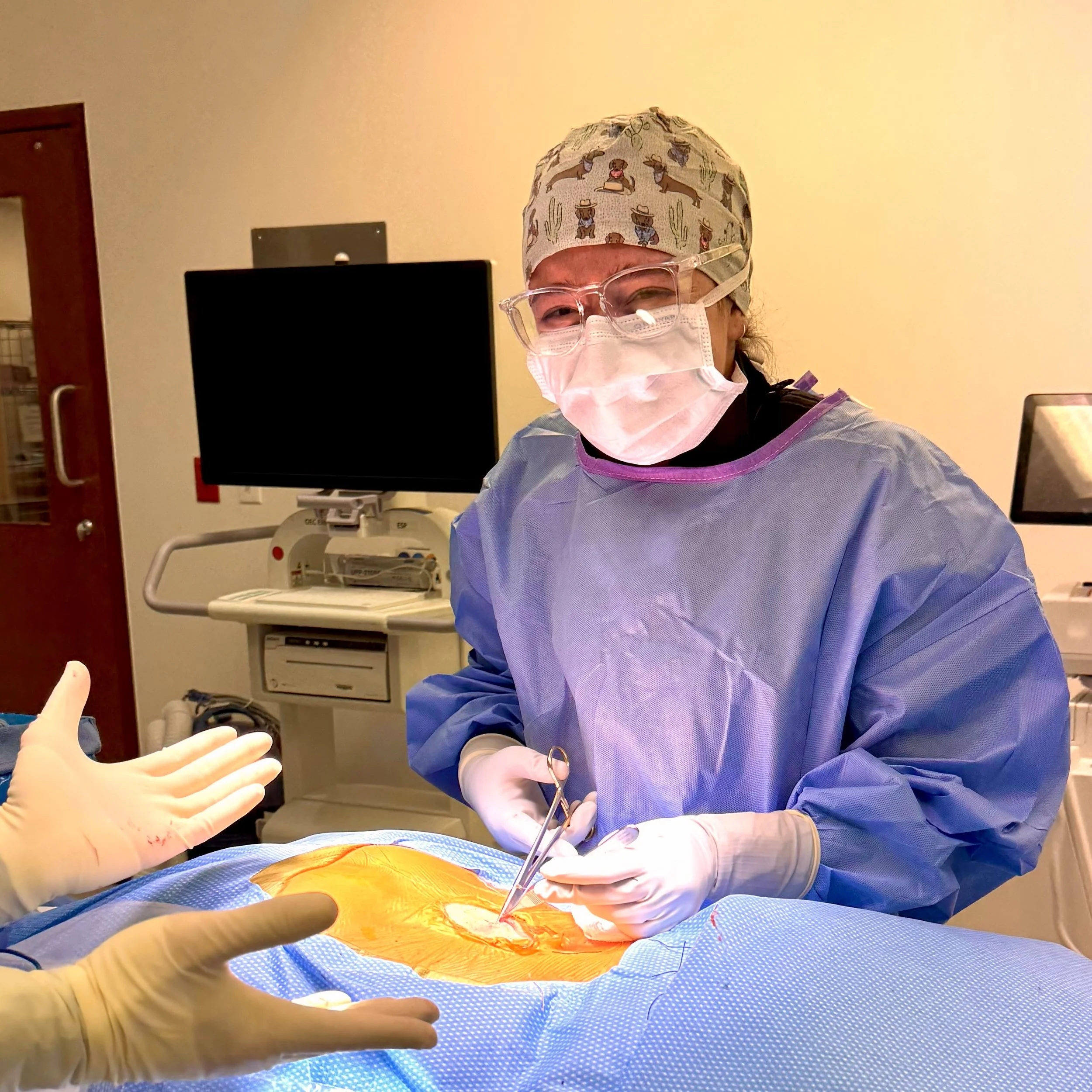 Claire in the operating room, wearing a surgical gown, cap, mask, and gloves. She is assisting in a surgical procedure.