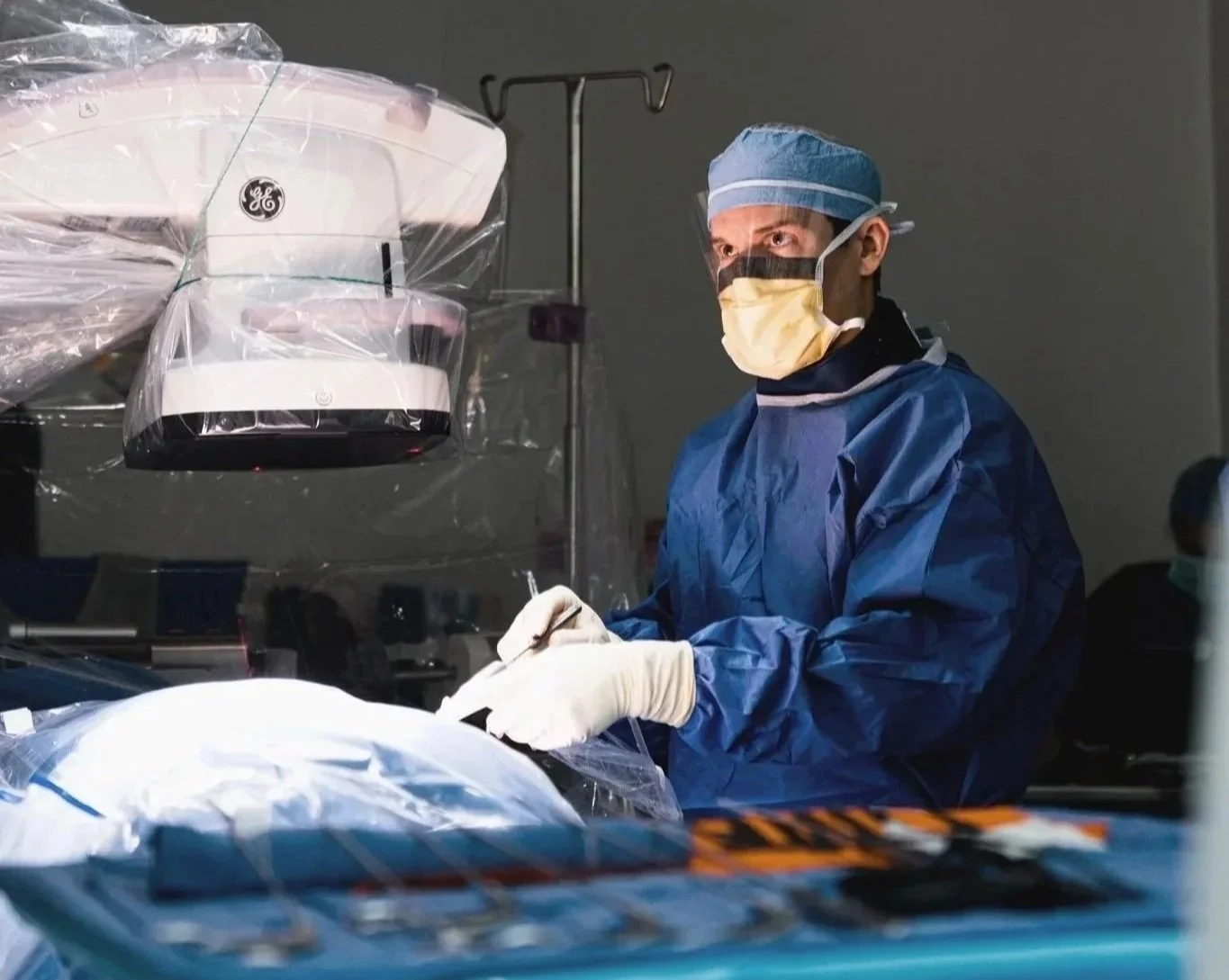 Dr. Derman wearing surgical attire, performing endoscopic spine surgery in an operating room.