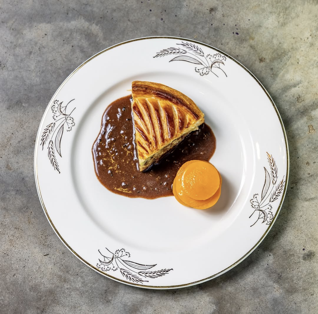 A slice of rabbit pithivier with butternut squash mille feuille and black truffle rabbit jus