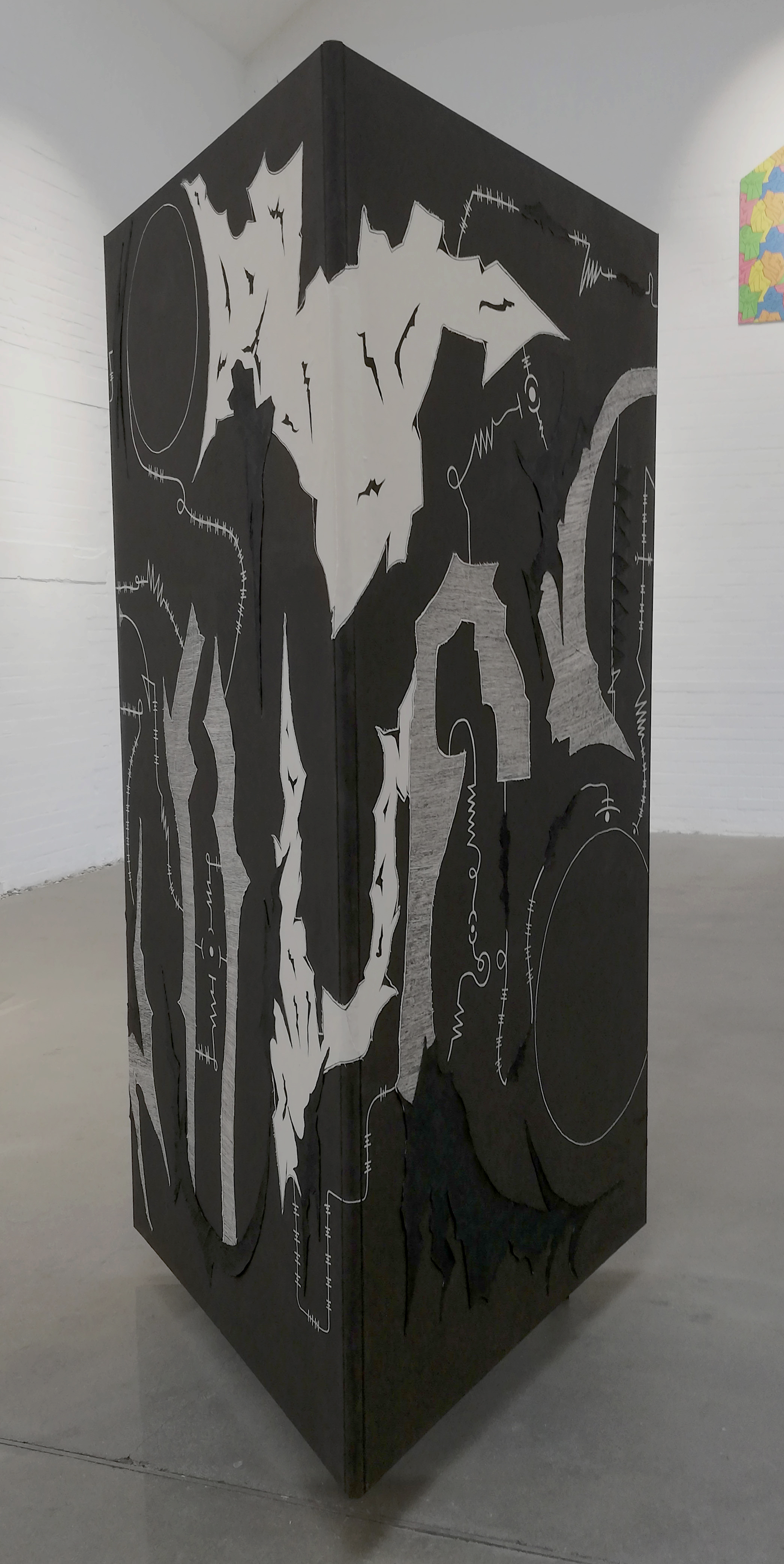 Dokumentation der durch Julian Schomäker gefertigten Arbeit o.T. Zu sehen ist ein Triptychon, das als Dreieck angeordnet, als Objekt frei im Raum steht. Es handelt sich um eine Leinwandcollage aus verschiedenen Formen, die an eine Landschaft erinnern