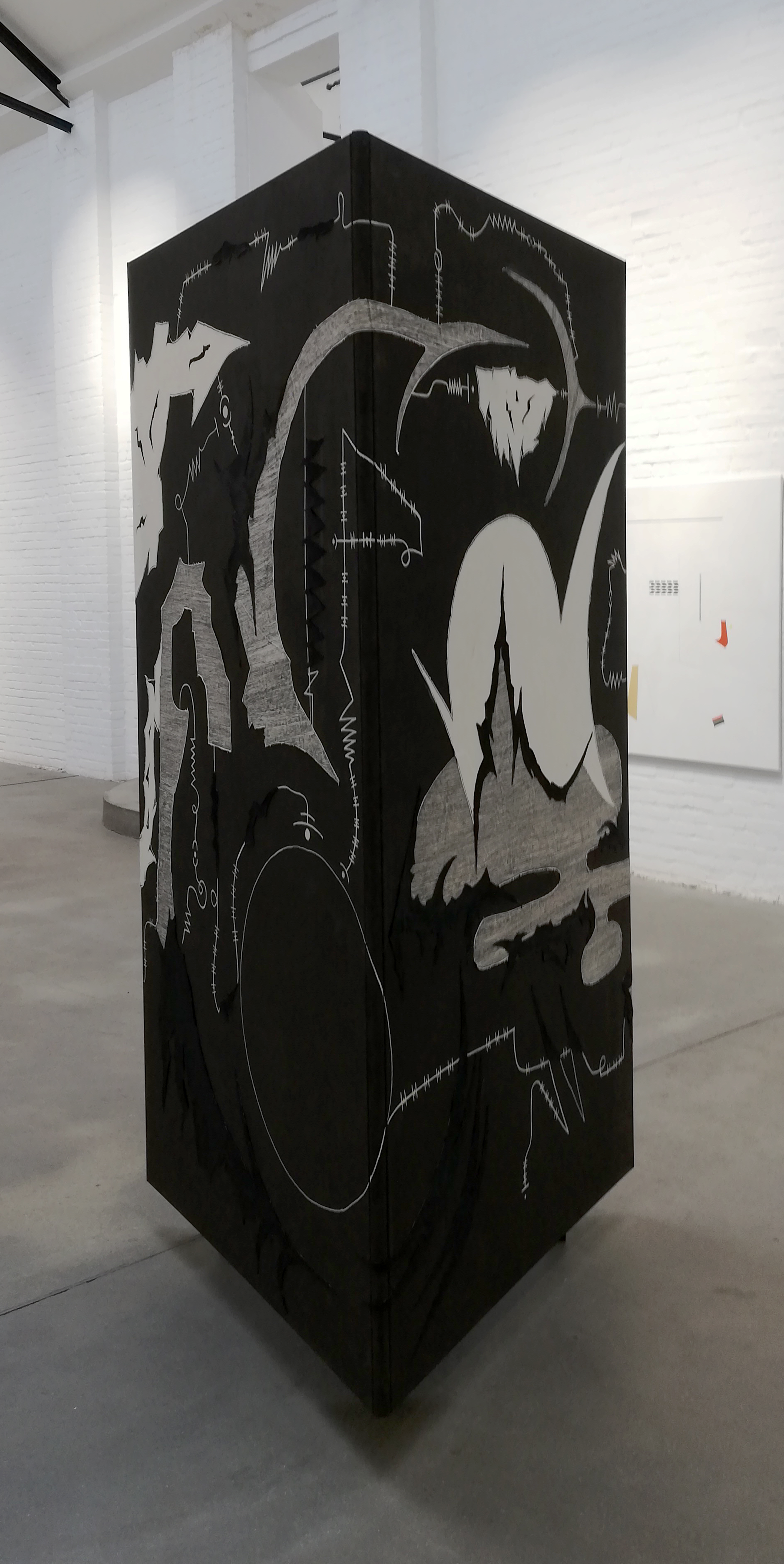 Dokumentation der durch Julian Schomäker gefertigten Arbeit o.T. Zu sehen ist ein Triptychon, das als Dreieck angeordnet, als Objekt frei im Raum steht. Es handelt sich um eine Leinwandcollage aus verschiedenen Formen, die an eine Landschaft erinnern