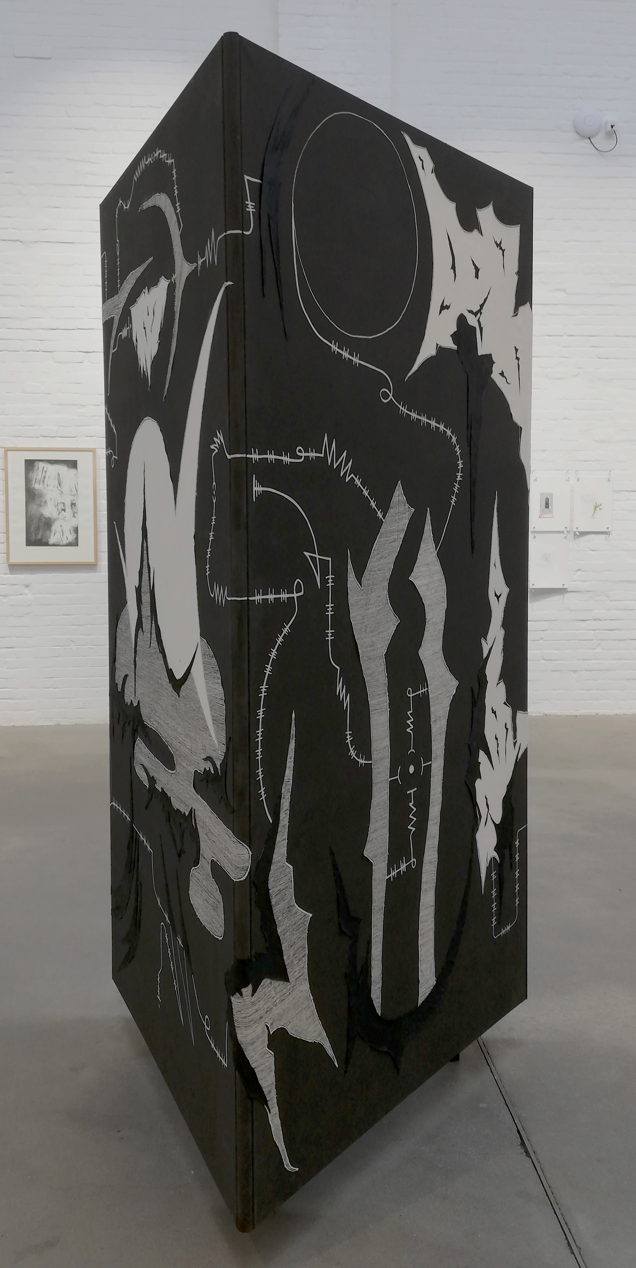 Dokumentation der durch Julian Schomäker gefertigten Arbeit o.T. Zu sehen ist ein Triptychon, das als Dreieck angeordnet, als Objekt frei im Raum steht. Es handelt sich um eine Leinwandcollage aus verschiedenen Formen, die an eine Landschaft erinnern
