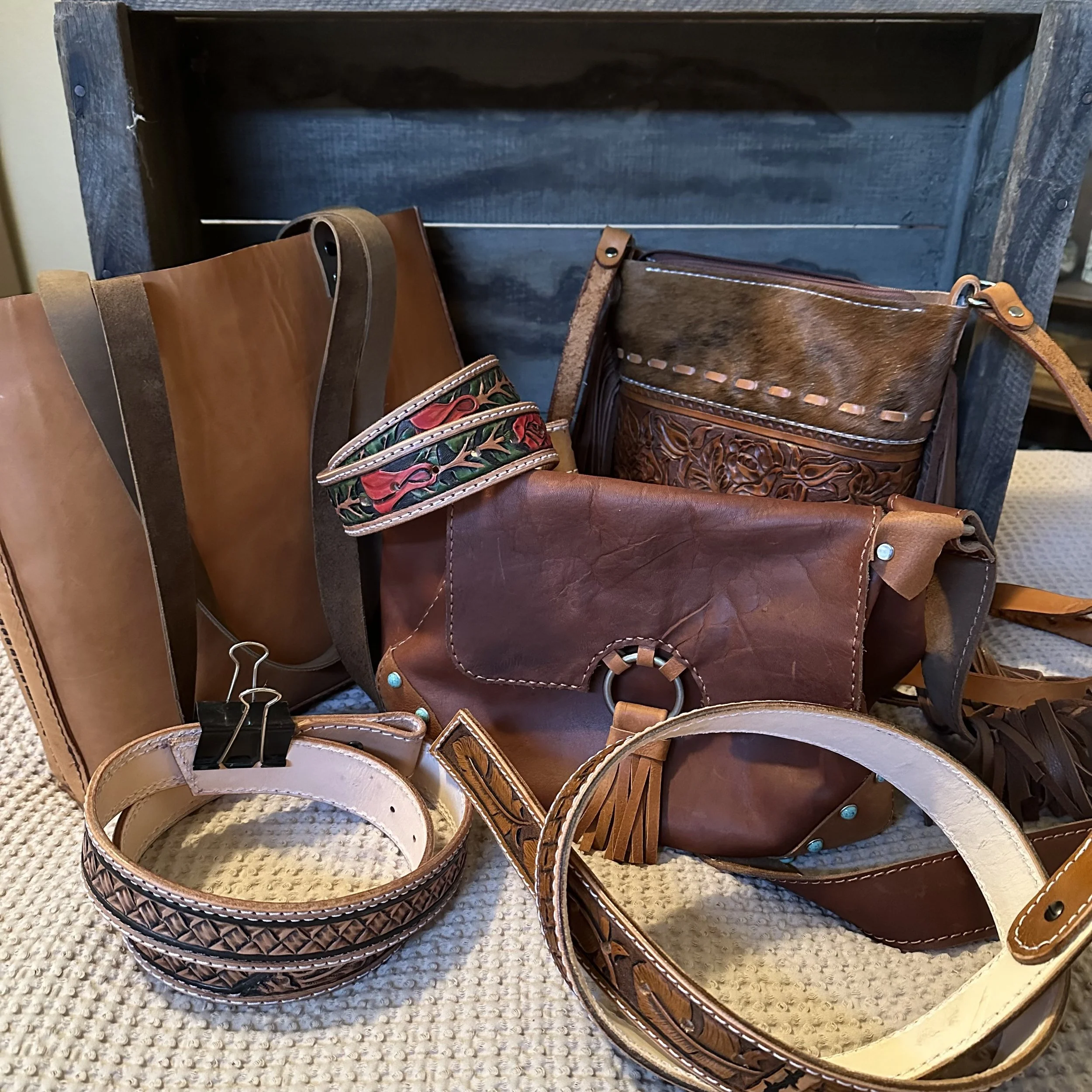 A collection of leather belts and accessories displayed on a wooden surface.