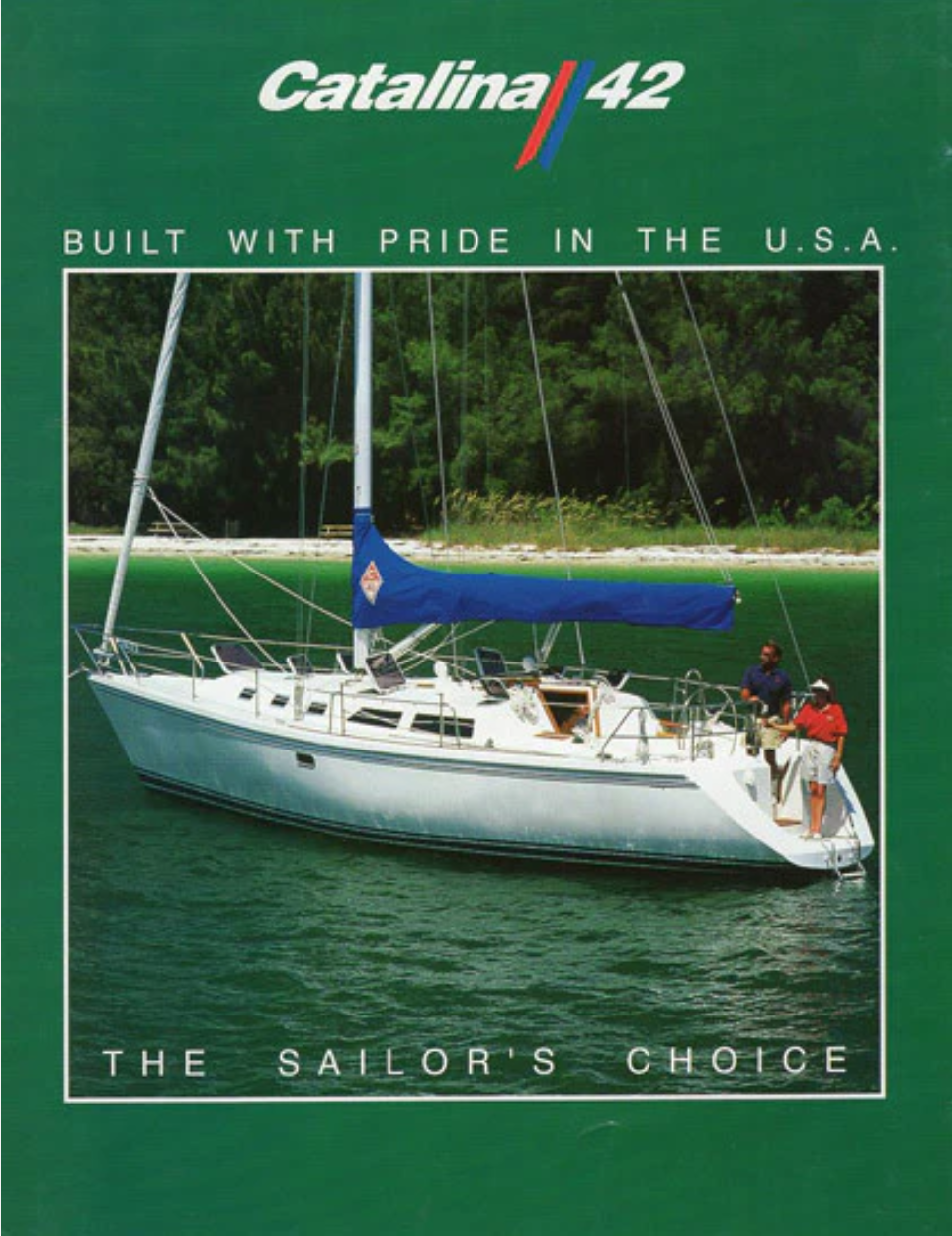 A Catalina 42 sailboat on calm water with two people on the stern, with a lush green shoreline in the background.