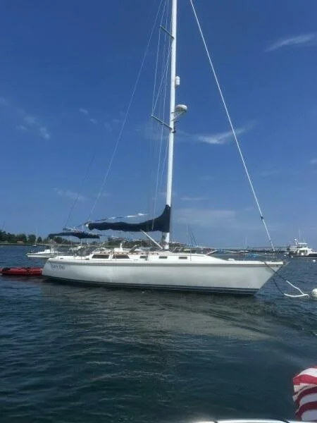 White sailboat docked on calm water under a blue sky