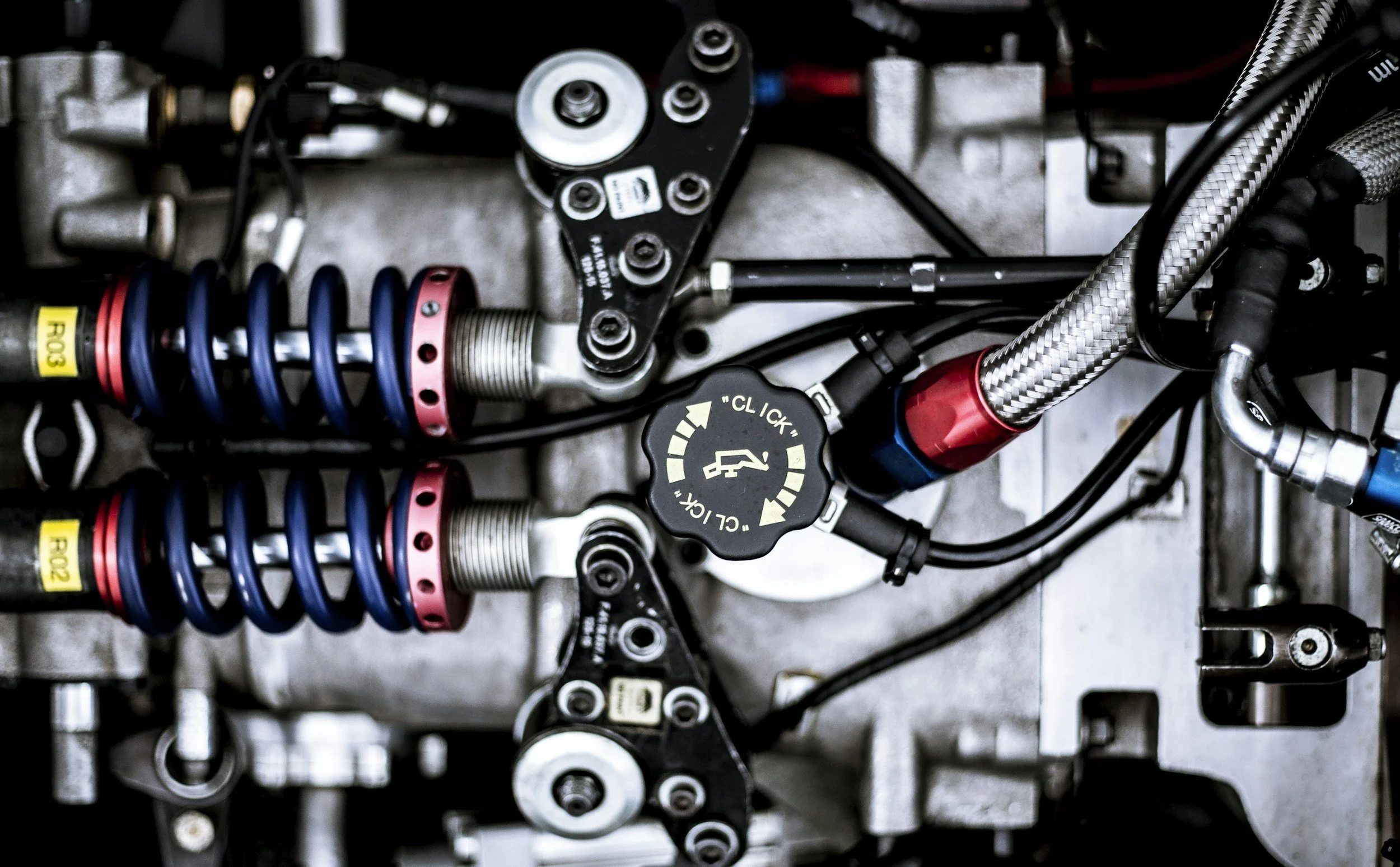 Close-up view of mechanical parts, including springs, hoses, and metal components, on a vehicle or machinery.