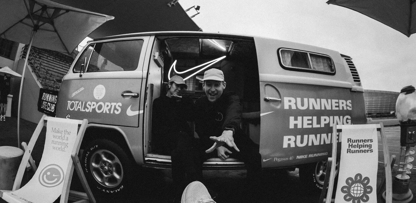 Black-and-white photo of a running community van with Runners Helping Runners graphics.