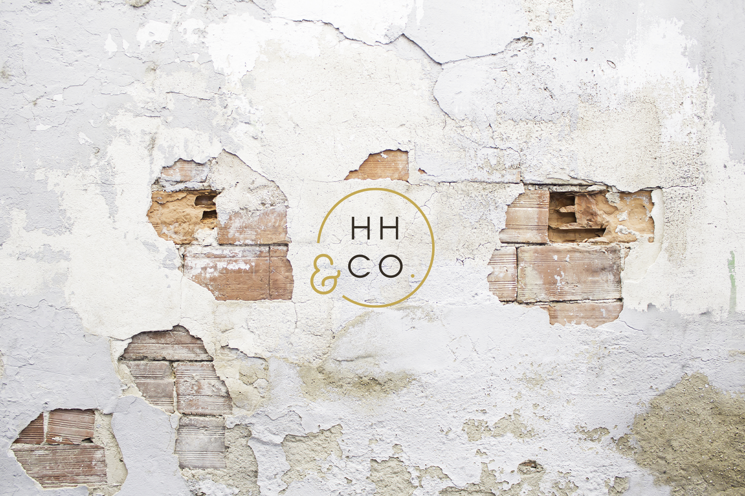 A distressed white brick wall with peeling paint and exposed bricks, featuring a logo with the text "HH & CO." inside a circle.