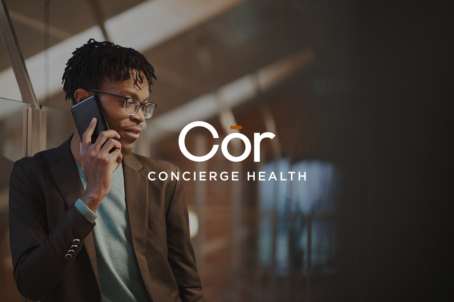 A man in business attire talking on a cell phone in an indoor setting with wooden ceiling beams and a modern decor, with the text 'Côr Concierge Health' overlayed.