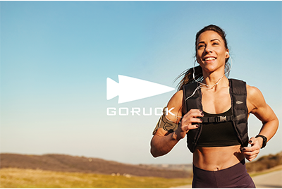 Smiling woman running outdoors with a backpack in a rural landscape