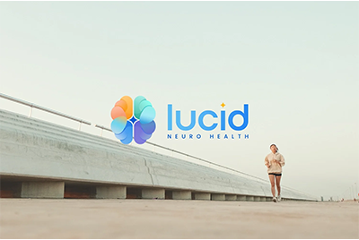 A person walking along a walkway with a large Lucid Neuro Health logo in the background.