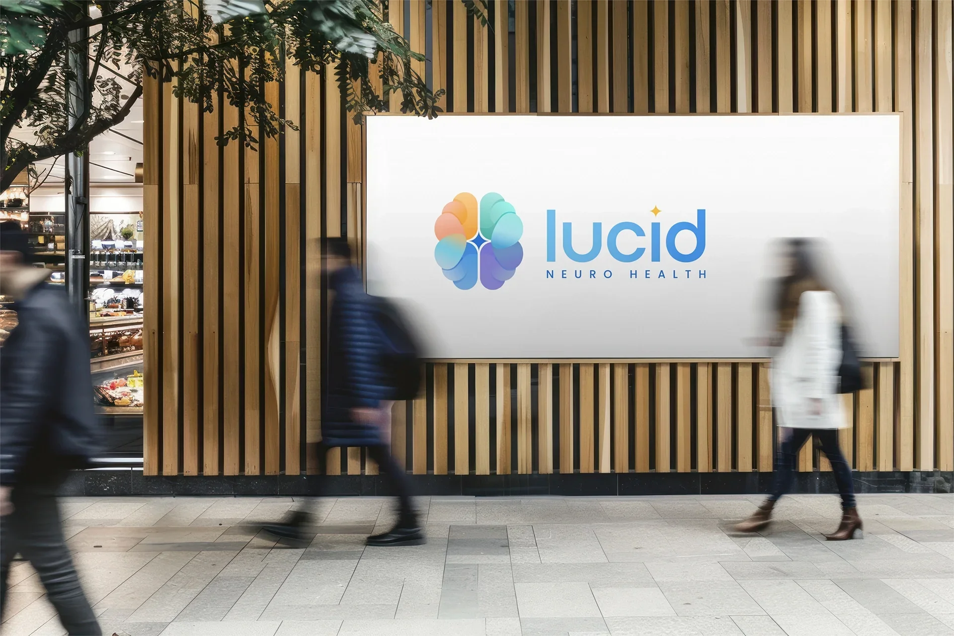 Sign for Lucid Neuro Health displayed on a large screen in a shopping mall or busy public space, with blurred pedestrians walking past.