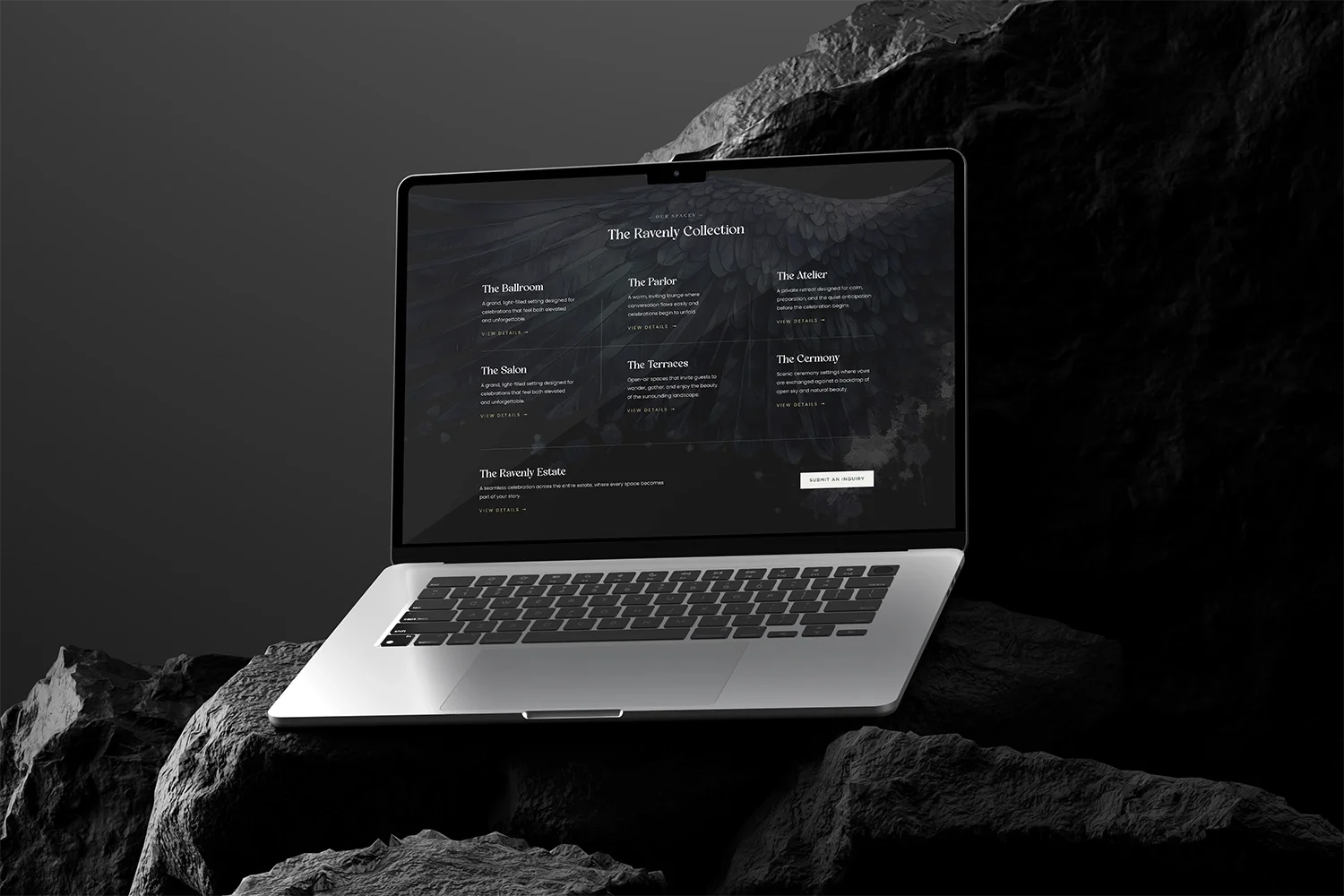 A laptop displaying a dark-themed website called 'The Ravenly Collection' with various sections, placed on a rocky surface.