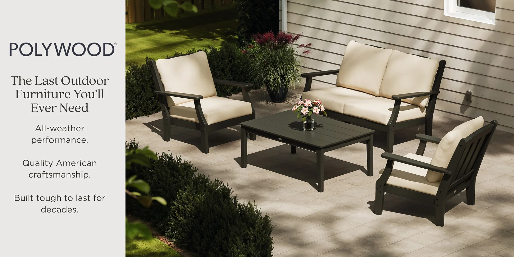 Outdoor patio furniture set with beige cushions, including a loveseat, two armchairs, and a coffee table, on a tiled patio next to a house with siding, decorated with pink and purple flowers and green plants.