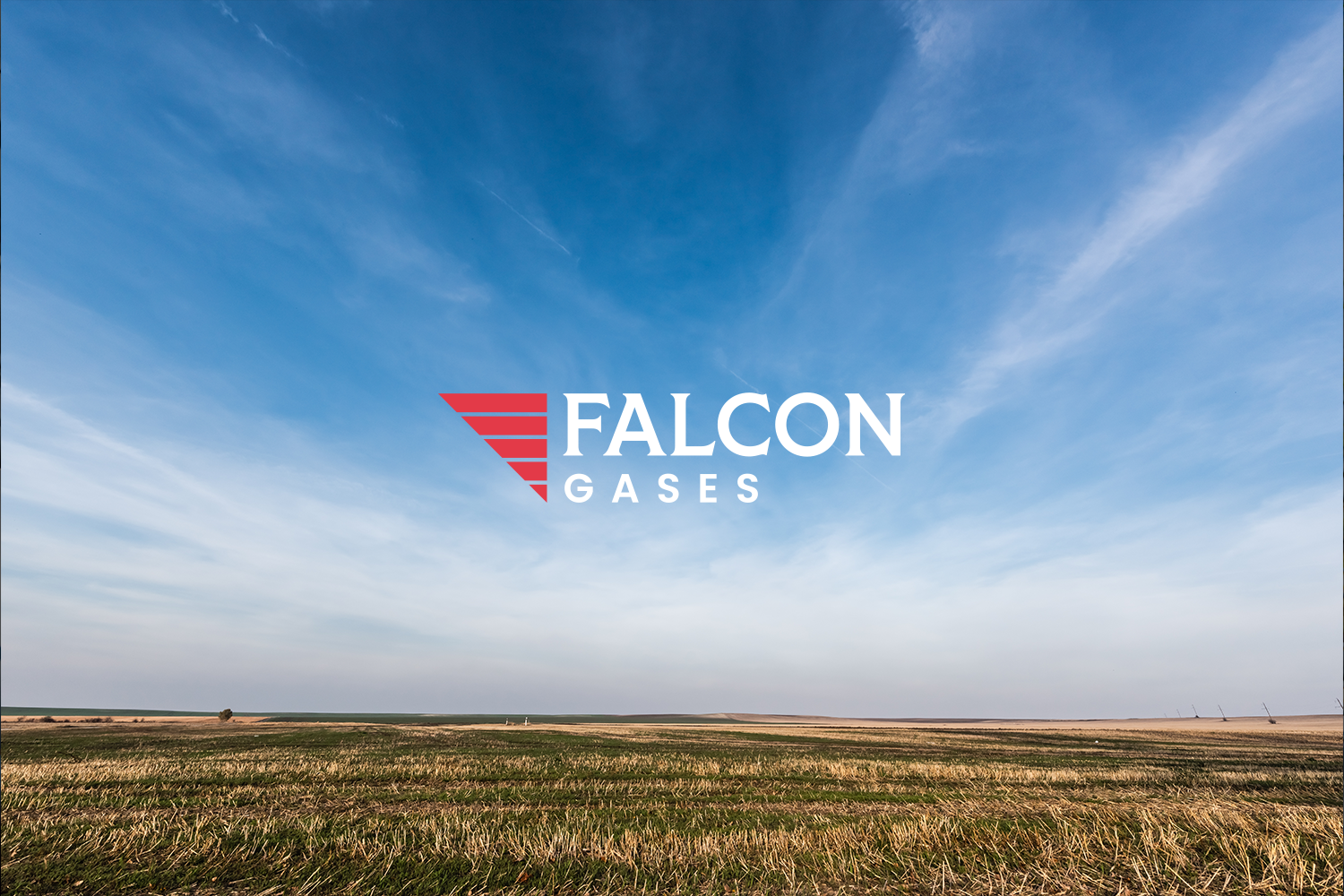 Open field with blue sky and light clouds, Falcon Gases logo with red and white design and text in the center