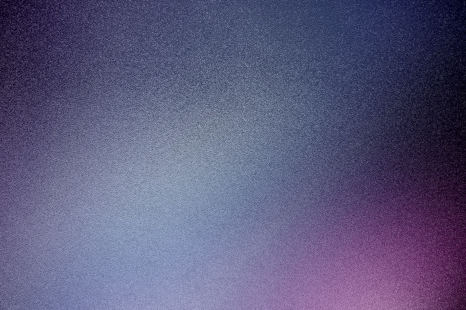 A close-up of a textured, metallic surface with a gradient of purple, blue, and gray colors.