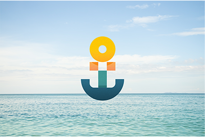 Colorful abstract sculpture floating above the ocean surface with blue sky and clouds in the background.