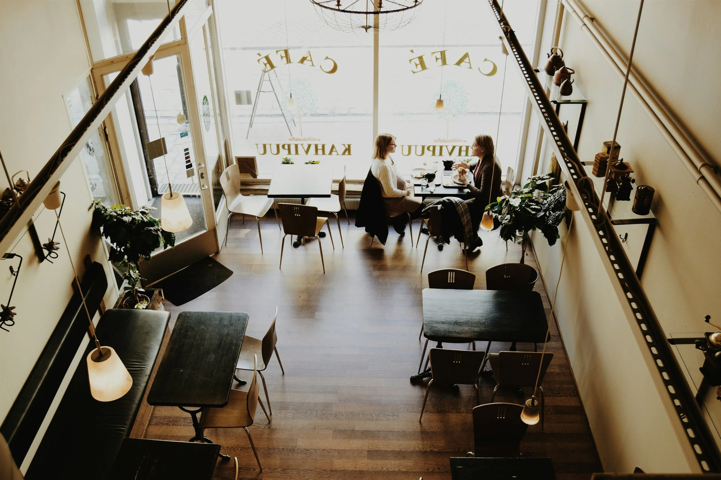 Two people are sitting in a coffee shop having a conversation. The image is intended to reflect the experience of two people who are not walking alone in their life's journey.