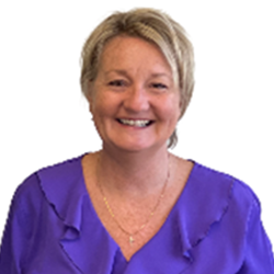 A smiling woman with short blonde hair wearing a purple top, against a white background.