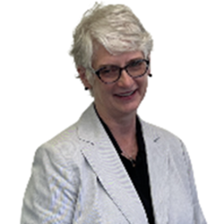 Smiling elderly woman with short white hair, wearing glasses and a white blazer.