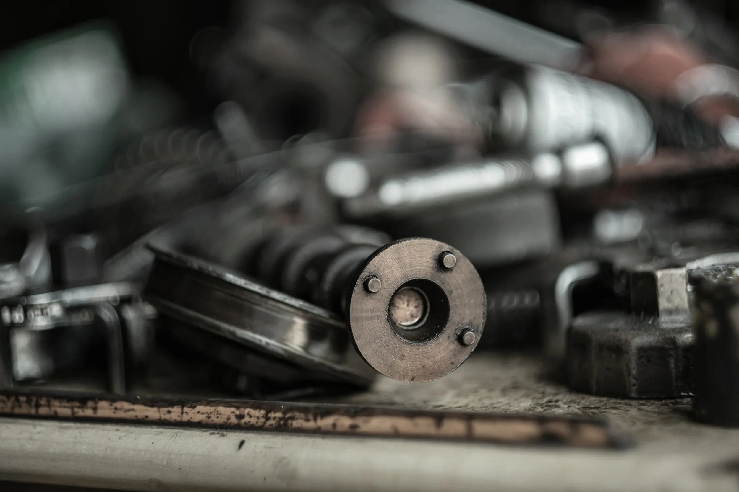 Close-up of a metal cogwheel in a machine with blurred mechanical parts in the background.