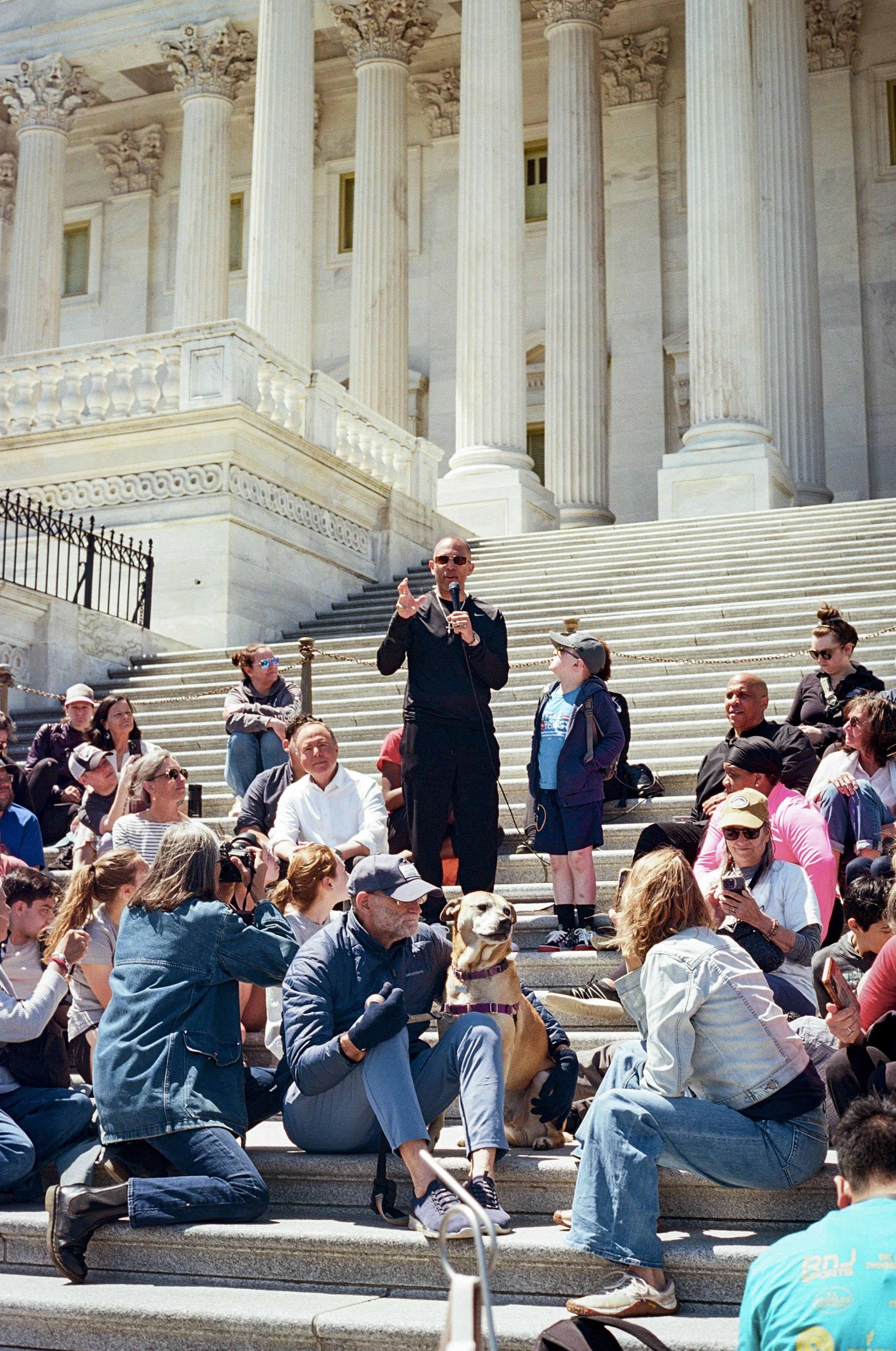 Leader Hakeem Jeffries speaks to a crowd seated on the steps of the House of Representatives.