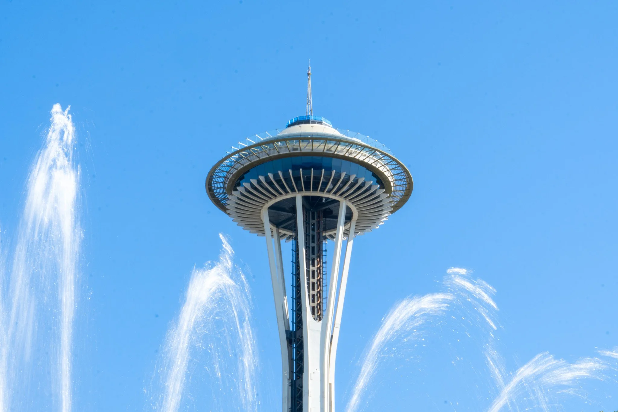 The Space Needle with a fountain in the foreground and a clear blue sky.