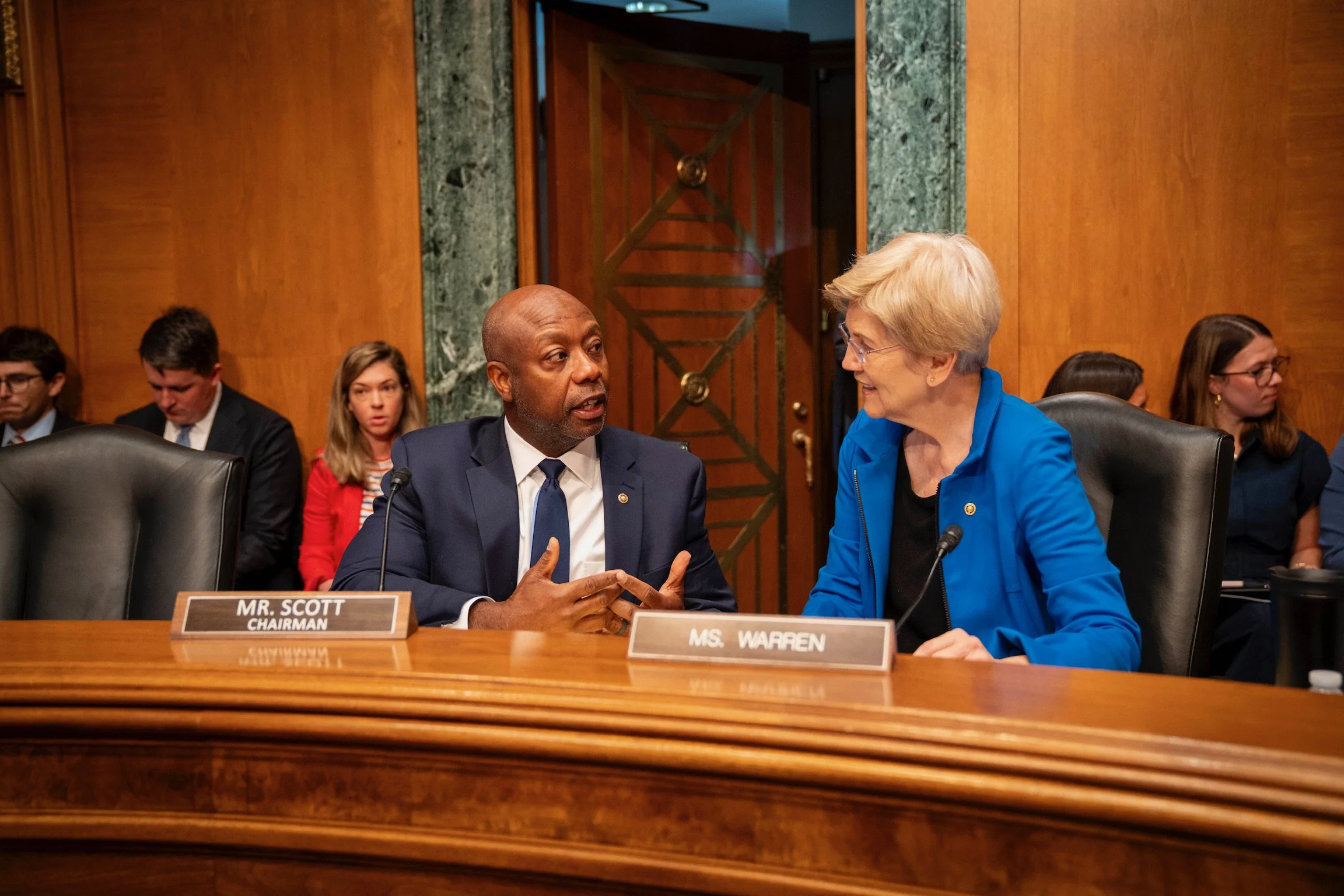 Sen. Tim Scott and Sen. Elizabeth Warren talk together at a Senate Banking committee hearing.