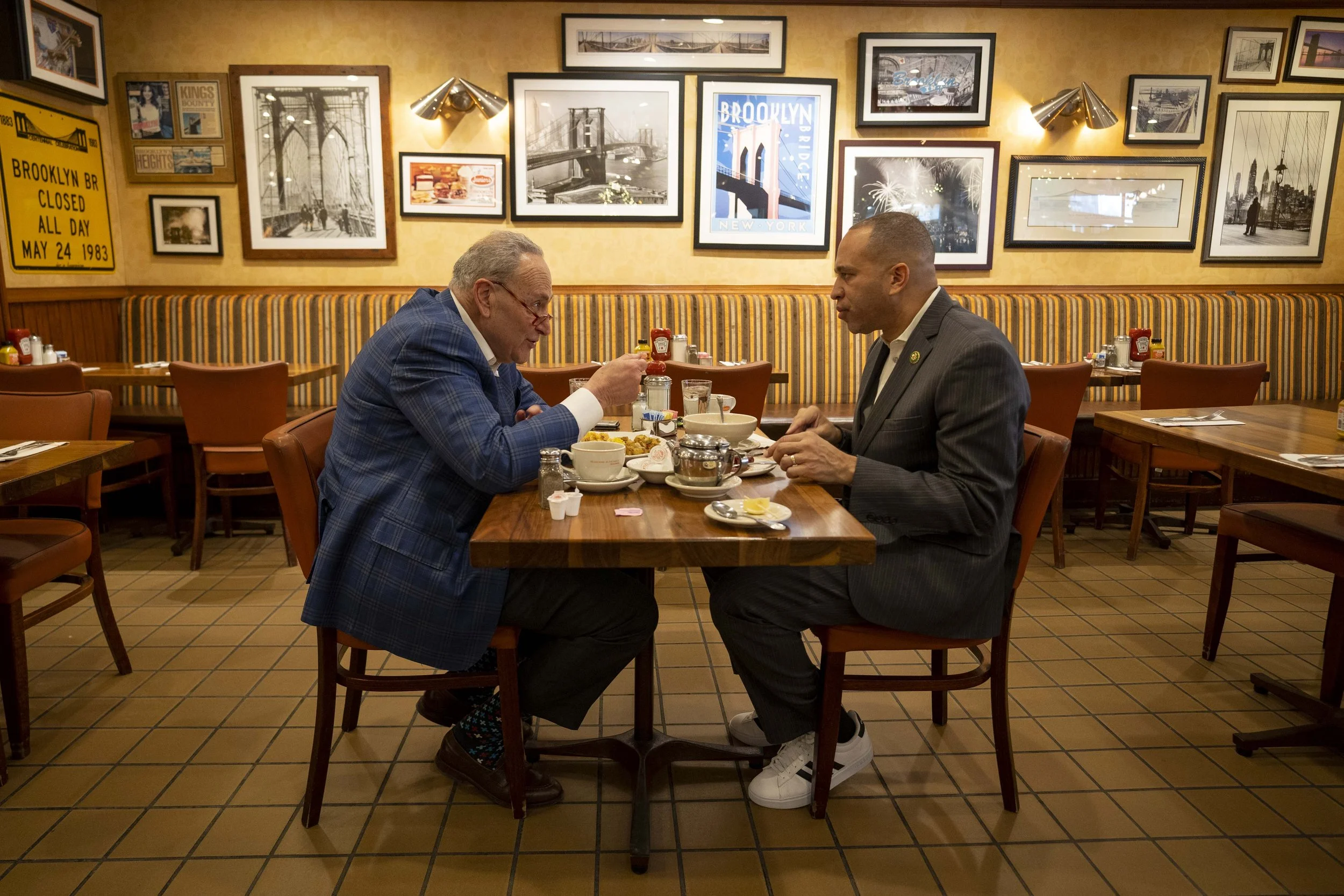Sen. Chuck Schumer and Leader Jeffries sit across from each other at Junior's, with lots of Brooklyn pictures on the wall in the background.