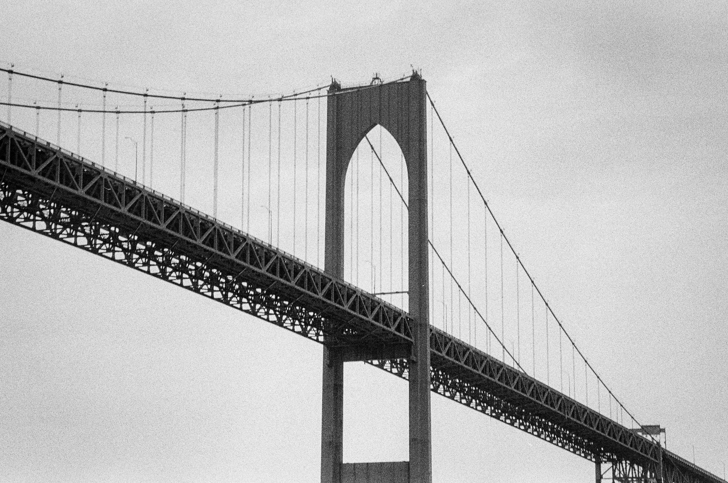 Black and white photo of a large suspension bridge with towers and cables.