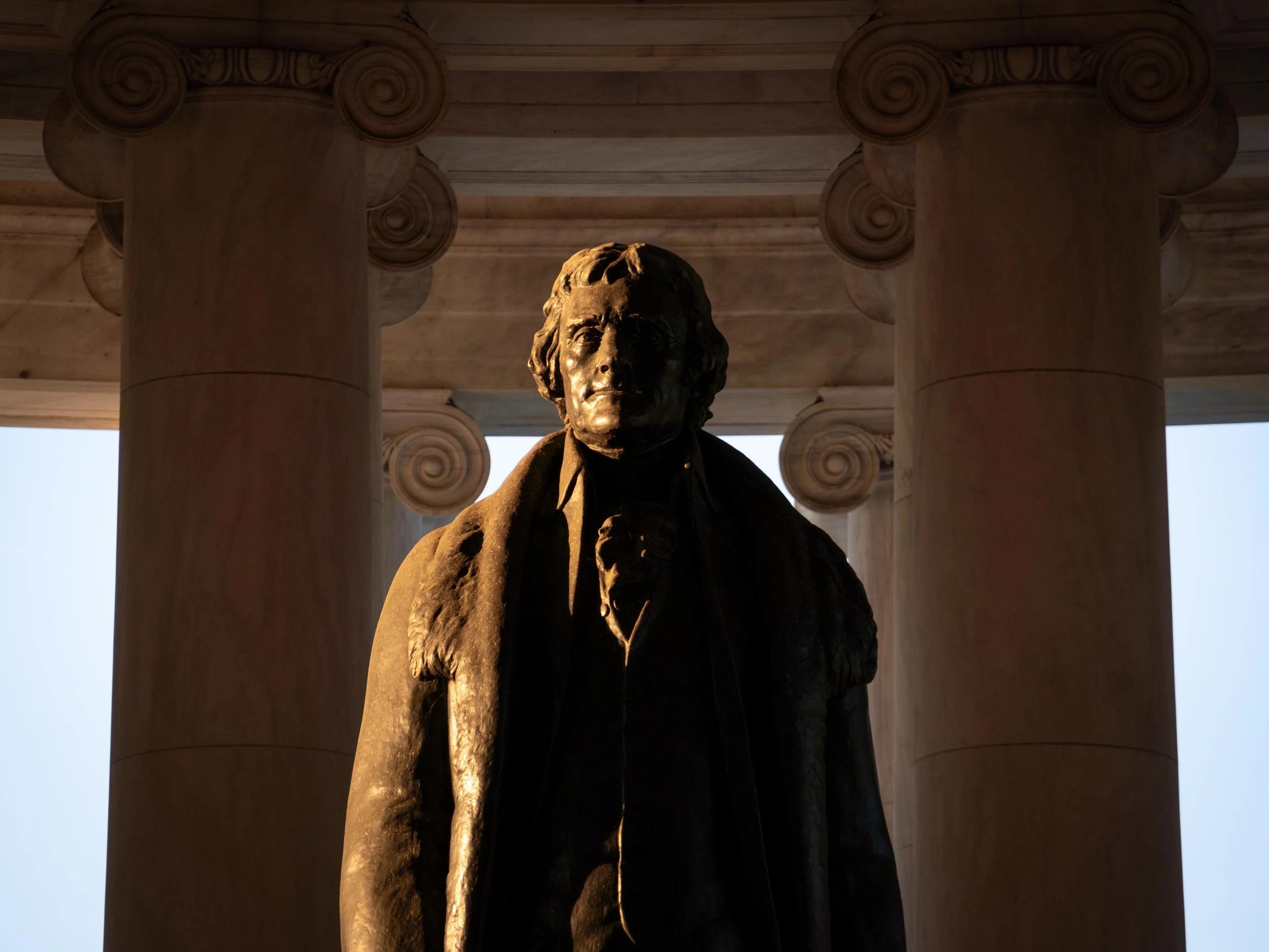 Statue of Thomas Jefferson, positioned against large stone columns with decorative capitals.