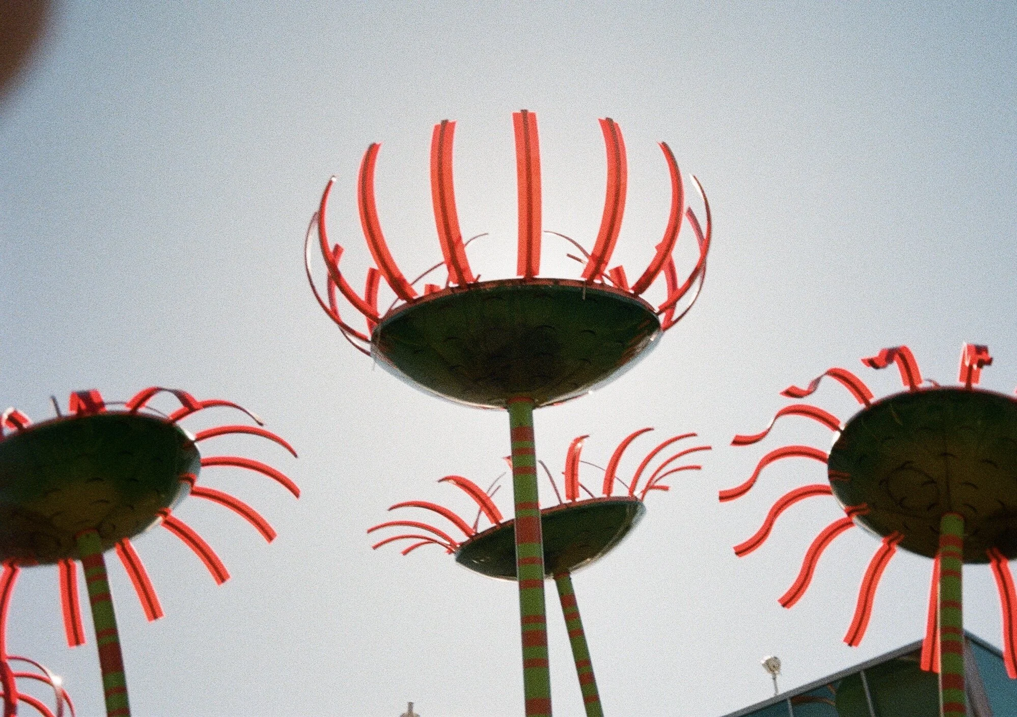 Colorful sculpture with red, curved metal arms and black base, set against a clear sky.