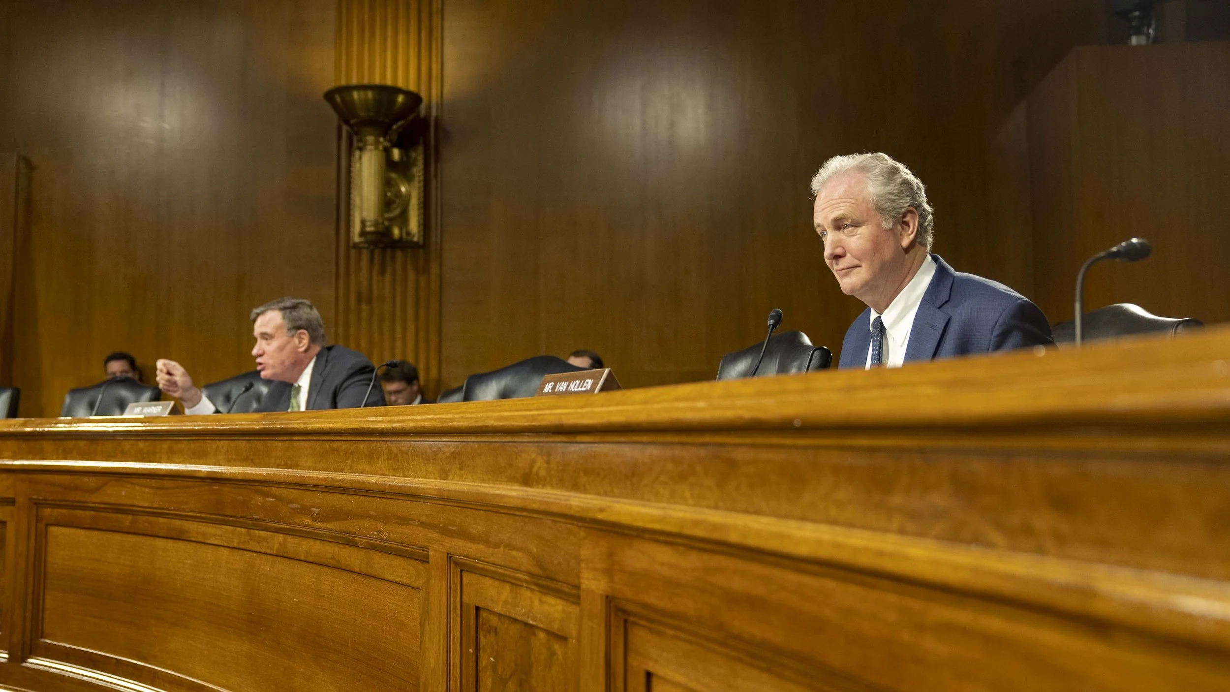 Sen. Chris Van Hollen watches from behind the dais at a Senate hearing.