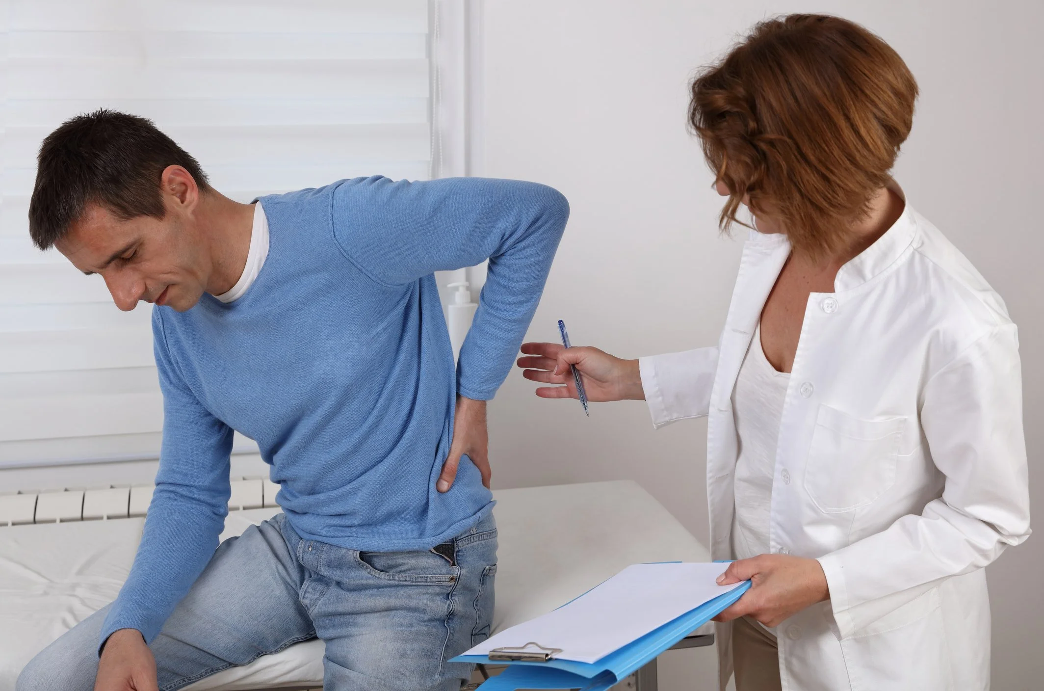 Man experiencing lower back pain during a clinical consultation — chronic pain care at CranioSacral Nashville