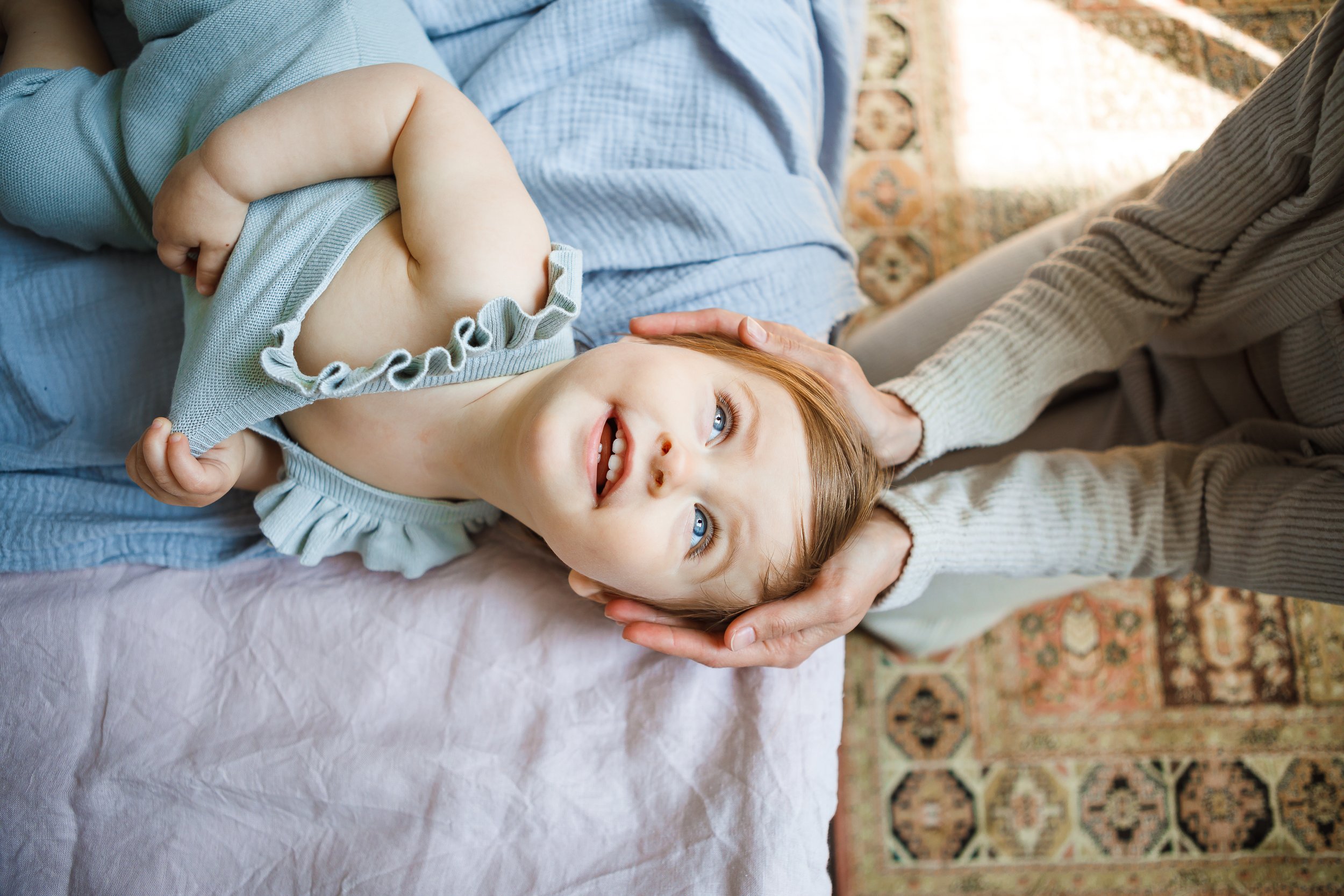 a happy toddler is held with head support while smiling